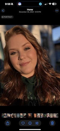 a young woman sitting on a wall next to the ocean